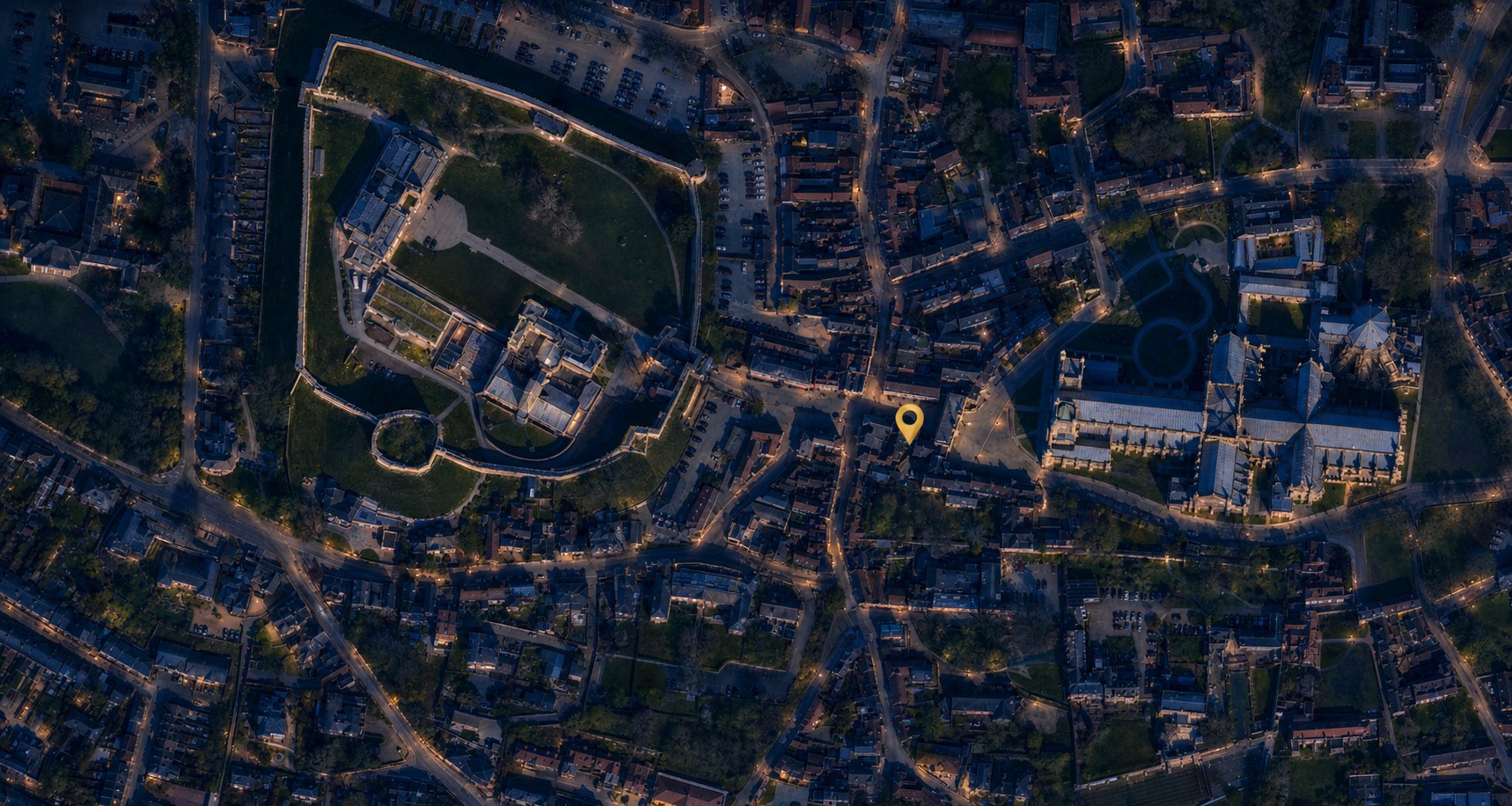 Label-free aerial view of Lincoln Castle and Lincoln Cathedral with a single gold pin marking Exchequergate
